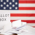 Rural America Blast Backfires—Campaign Implodes Ballot box with papers in front of an American flag