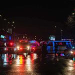 3 Dead, 6 Injured After Minneapolis Shooting Nighttime police scene with flashing lights on a wet city street