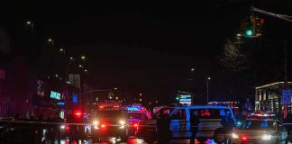 3 Dead, 6 Injured After Minneapolis Shooting Nighttime police scene with flashing lights on a wet city street