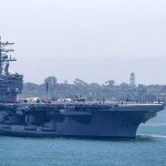 Multiple Sailors Try to Go Overboard From USS Abraham Lincoln Aircraft carrier escorted by a tugboat in a harbor