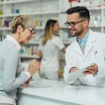 Healthcare Shock: 2026 Premiums Surge Pharmacist assists customer at pharmacy counter