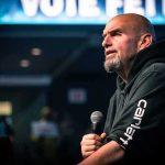 Democrats CROSS PARTY LINES to Support a Republican?! Bald man in a hoodie speaking into a microphone on stage