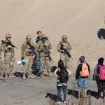 300 Hostages Freed From Militant Captivity Soldiers stand behind barbed wire facing civilians