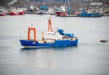 Arctic Showdown: Norway Grabs Russian Ship Blue research vessel in harbor with orange cranes