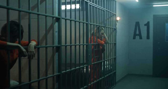 shutterstock_2334417543 prison cell with inmates in orange jumpsuits behind bars