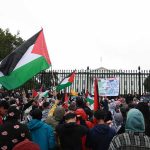 Hezbollah Flags Wave Amid NY Synagogue Chaos Crowd holding flags and signs outside a fenced government building