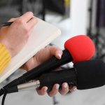 Iran Threatens South Korean If It Joins Hormuz Mission Journalist holding two microphones while writing in a notebook