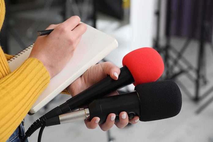 shutterstock_2431198207-6 Journalist holding two microphones while writing in a notebook