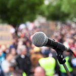 Armed Man CHARGES Toward Dem Governor Candidate microphone on stand in front of a blurred crowd