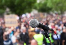Armed Man CHARGES Toward Dem Governor Candidate microphone on stand in front of a blurred crowd