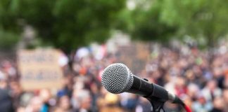 Armed Man CHARGES Toward Dem Governor Candidate microphone on stand in front of a blurred crowd