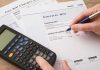 80% Higher Power Bills? There’s More to It hand reviewing utility bills with calculator on desk