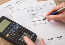 80% Higher Power Bills? There’s More to It hand reviewing utility bills with calculator on desk