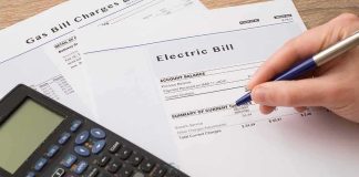 80% Higher Power Bills? There’s More to It hand reviewing utility bills with calculator on desk