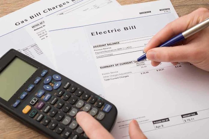 shutterstock_523848388 hand reviewing utility bills with calculator on desk