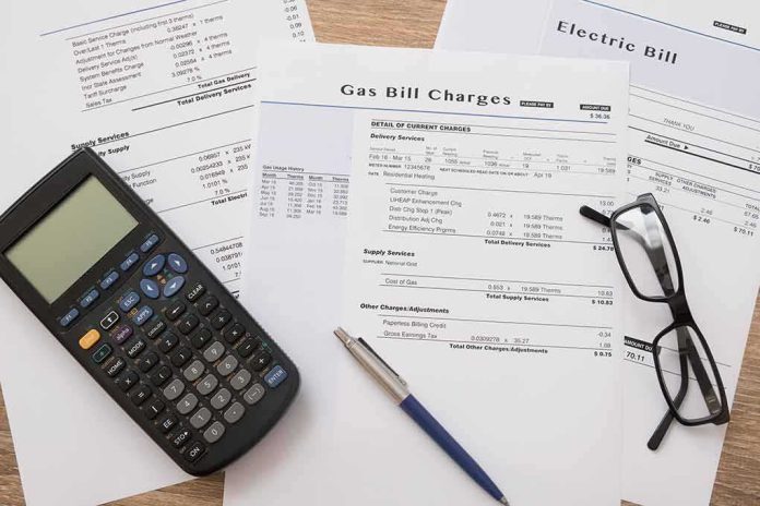 Utility bills with calculator, pen, and eyeglasses on a desk