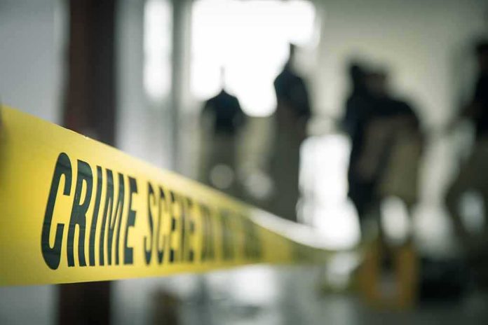 shutterstock_579245569 Crime scene tape with investigators in the background