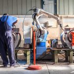 Iran Unleashed 4,400 Kamikaze Drones and Building 10,000 a Month Factory worker operates near an industrial robot arm in a workshop