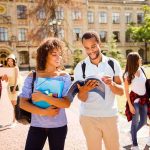 College students walking on campus with books and backpacks