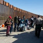 Trump DOJ Takes Border WALL Fight to Supreme Court Group of people standing by a border fence with officers and vehicles