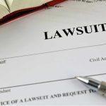 NYC Says Law Firm FAKED Slip-and-Fall Claims Lawsuit document with a pen and book.
