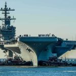TOILET Failures Sideline Navy’s Priciest Carrier Aircraft carrier guided by tugboats in a harbor