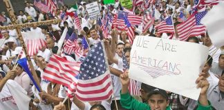 Josh Boyce and crowd at a demonstration waving American flags