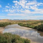 Texas Moves to Lock CARTELS Off Islands River winding through a desert valley under a blue sky