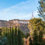 Hollywood Money Is FLEEING America Hollywood Sign on hillside framed by trees