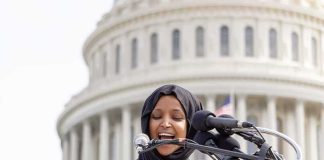 Ilhan Omar Doubles Down on ABOLISHING ICE Woman in hijab speaking at podium with microphones