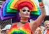 Pastor Found GUILTY Over Drag Story Hour Protest Drag performer in vibrant rainbow costume raising an arm at a parade