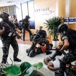 American Among the DEAD in Airport Attack Tactical police detain suspects in an office lobby