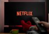 Woke Netflix Is in TROUBLE TV screen with Netflix logo and person holding remote