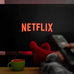 Woke Netflix Is in TROUBLE TV screen with Netflix logo and person holding remote