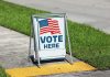 A-frame sidewalk sign with American flag and vote message