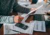 20 Million Seniors Getting Surprise Medicare Cash Person reviewing bills with calculator at cluttered desk