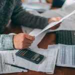 20 Million Seniors Getting Surprise Medicare Cash Person reviewing bills with calculator at cluttered desk