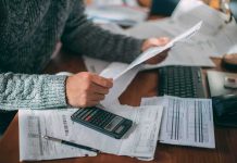 20 Million Seniors Getting Surprise Medicare Cash Person reviewing bills with calculator at cluttered desk