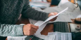 20 Million Seniors Getting Surprise Medicare Cash Person reviewing bills with calculator at cluttered desk