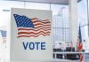 Judge Rules Noncitizen Voting Ban UNCONSTITUTIONAL Voting booth with American flag design in a modern polling place
