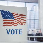 Judge Rules Noncitizen Voting Ban UNCONSTITUTIONAL Voting booth with American flag design in a modern polling place