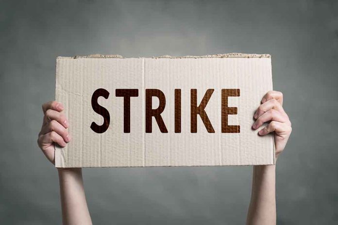 683350906 featured image Two hands holding a cardboard sign saying "STRIKE".