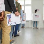 People standing in line holding voting papers