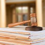 Gavel resting on stack of paperwork in courtroom