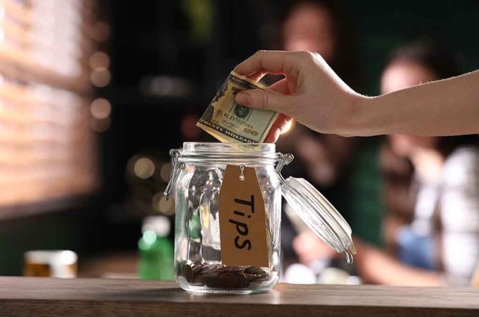 1951516207 featured image Hand placing dollar bill into a tip jar.