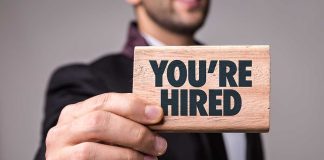 Person holding a You're Hired sign.