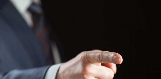 Person pointing with finger, wearing a suit
