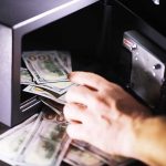 Hand putting cash into a safe