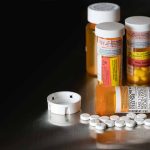 Pills and prescription bottles on a dark surface
