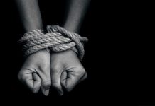 Hands tied with rope against black background